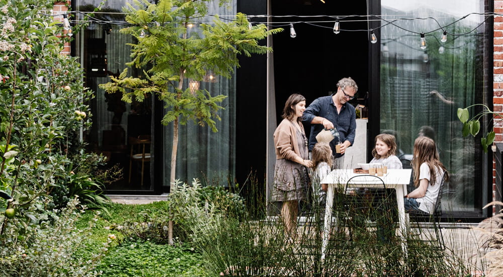 Family eating lunch in the garden of Australia's most sustainable house by Melbourne Design Studio